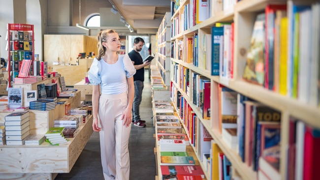 Studierende betrachtet Bücher in Buchhandlung © Markus Zahradnik